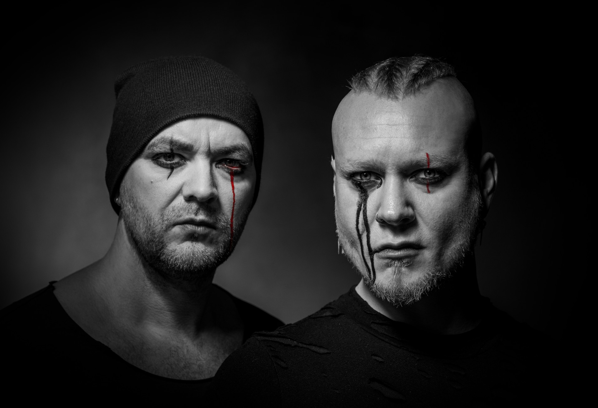 Ein Schwarz-weiß-Foto der Gesichter der beiden Musiker von Hard & Spades vor einem dunklen Hintergrund. Sie blicken ernst in die Kamera. Ihr Augen sind geschminkt, als würde ein schmaler Strom Blut herauslaufen.